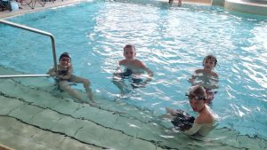 Vier Kinder am flachen Einstieg im Schwimmbecken.