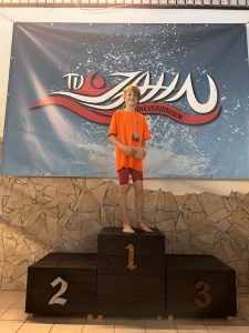 Kind im orangefarbenen Shirt und roten Shorts auf Platz eins.